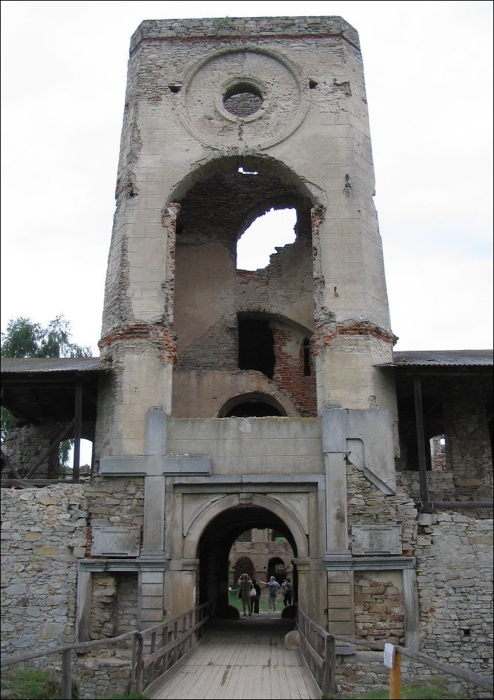 Ruines de la tour d’accès au château de Krzyżtopór. Un pont de bois jeté sur les fossés conduit jusqu’à l’entrée, une arche flanquée d’une croix et d’une hache monumentale. Elle est surmontée d’une tour de trois étages, aujourd’hui éventrée et évidée.