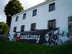 Une peinture murale occupe l’espace compris entre le gazon et les fenêtres d’une maison blanche à deux étages. Au centre, un large mur noir sur lequel est inscrit „Pamiętamy“ (nous nous souvenons) en grosses lettres. Le P a la forme de l’ancre, symbole de l’Armia Krajowa, aux couleurs blanc-rouge. Au dessus, en plus petit, est écrit «le 1er août, jour de gloire, le peuple de Varsovie s’est soulevé, pour libérer la Capitale du mal…». 
  À droite, deux insurgés, se détachent sur un fond de briques blanches. L’un, en béret et brassard blanc-rouge, est armé d’une mitraillette sten. L’autre, en casque allemand avec bandeau blanc-rouge, tient un cocktail molotov. S’ils se penchaient, ils verraient de leur position des ruines, puis la Vistule avec un pont détruit. 
  À gauche, la silhouette d’un insurgé, de profil, casque allemand au bandeau blanc-rouge, mitrallant des ruines. Au-dessus des ruines, l’inscription «63 jours de gloire».