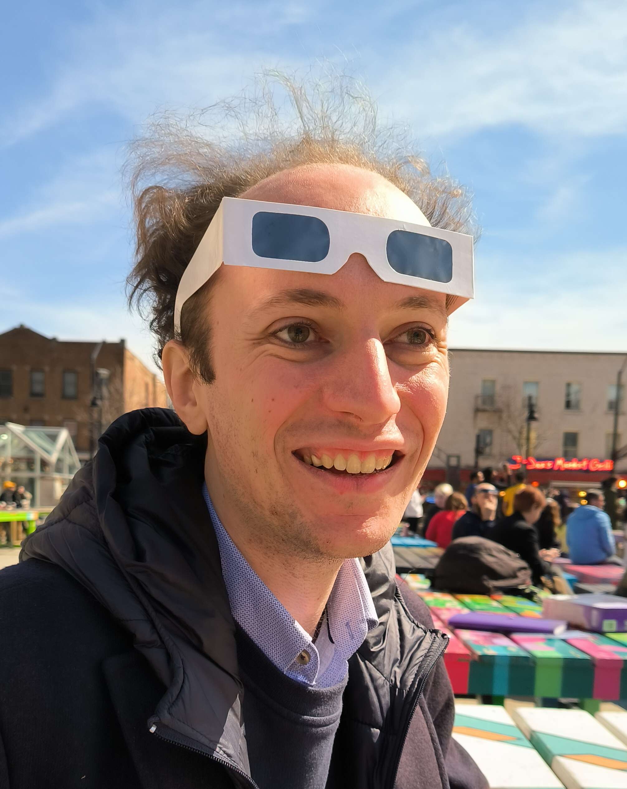 My face looking away from the camera with eclipse glasses on the forehead, 2024.